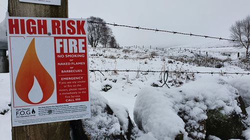 Text on snow covered road against sky