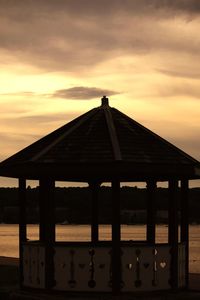 Silhouette built structure by sea against sky during sunset