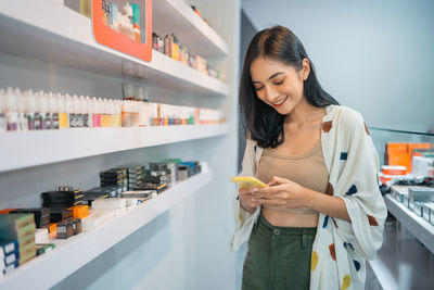 Side view of young woman using mobile phone at home