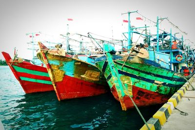 Fishing boats moored in sea against clear sky