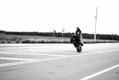 Man riding motorcycle on road against clear sky