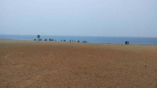 People on beach against clear sky