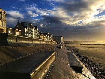 View of buildings by sea against cloudy sky