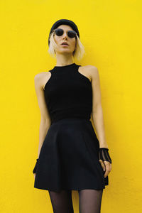 Stylish girl in black at the yellow wall .urban fashion style