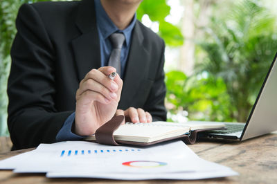 Midsection of man using mobile phone while sitting on table