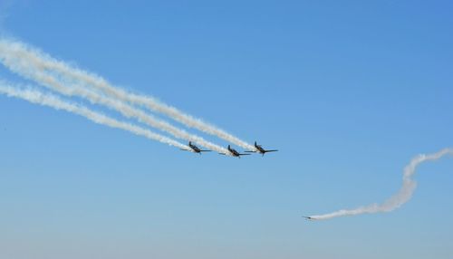 Low angle view of airshow against clear blue sky