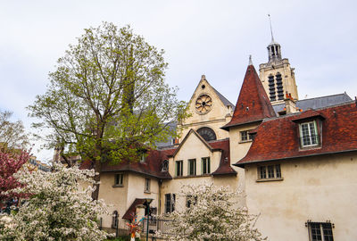 Low angle view of trees and building against sky