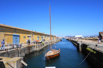 Boats moored in river with city in background