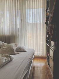 Pillows on bed against white curtain at home