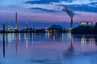 Reflection of smoke emitting from factory in river against sky