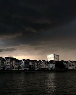 Sea by buildings against sky at dusk