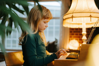 Young girl playing keyboard at home