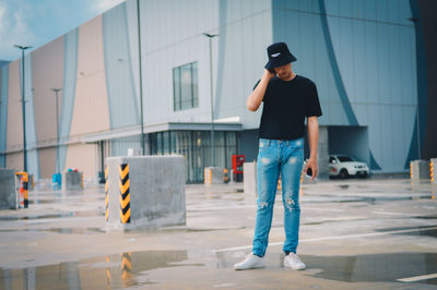 Full length of man standing on footpath against building