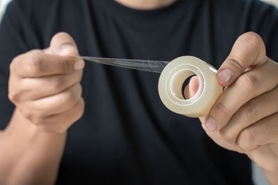 Midsection of man holding adhesive tape at home