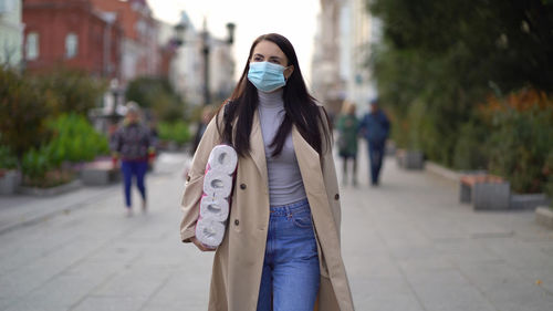 Woman walking on footpath in city