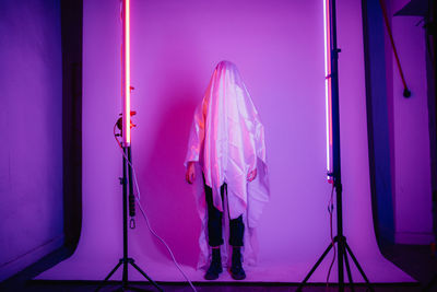 Woman with pink umbrella standing against illuminated lights