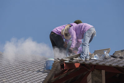 Rear view of people working against clear blue sky