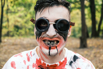 Portrait is close-up of face of zombie with traces of blood and black fluid flowing from the mouth. 