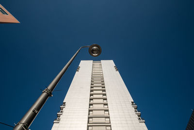 Low angle view of building and street light against clear blue sky