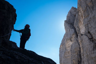 Silhouette of man standing on rock against sky