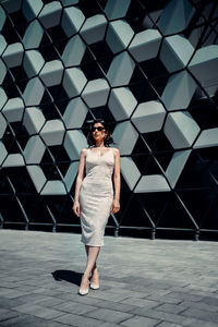 Full length portrait of woman standing against wall