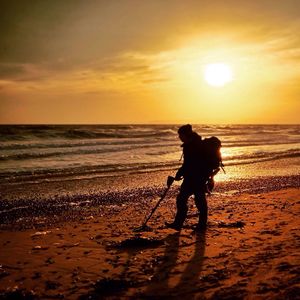 Silhouette of people on beach at sunset