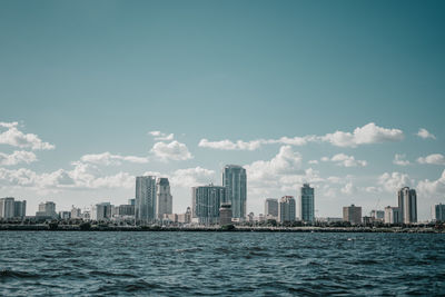 Sea by buildings against sky in city