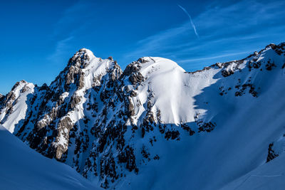 Scenic view of snowcapped mountains against blue sky