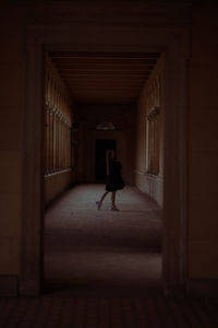 Full length of young woman standing in dark corridor