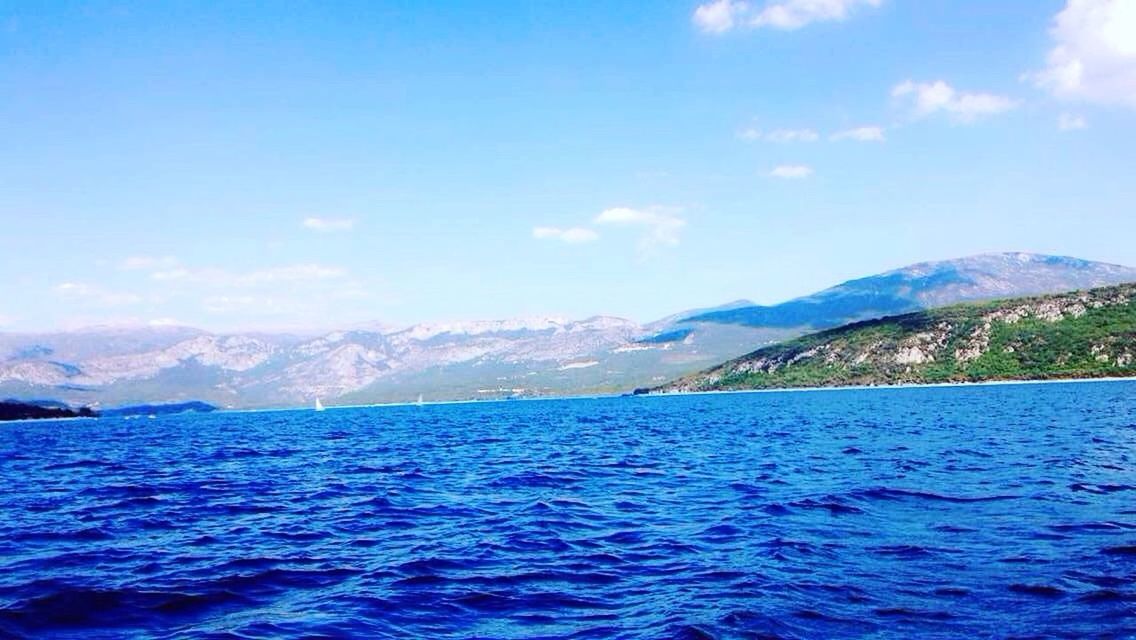 VIEW OF CALM SEA AGAINST MOUNTAINS