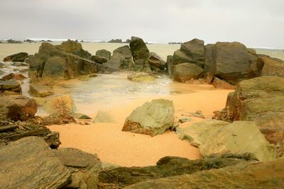 Rock formations on shore against sky