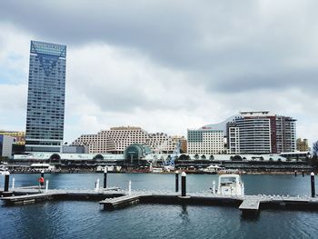 Modern buildings by river against sky in city