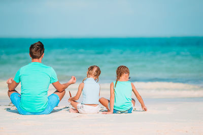 Rear view of women sitting on beach