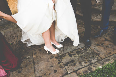 Low section of bride and bridegroom standing on footpath