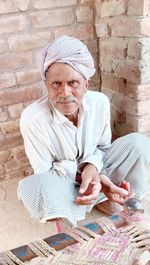 Portrait of mature man sitting against wall