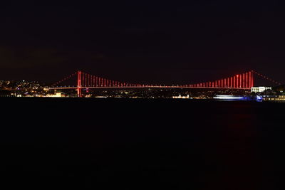 Illuminated bridge over calm sea at night