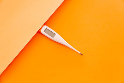 High angle view of thermometer on orange table