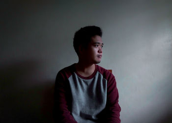 Portrait of young man looking away against white background