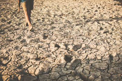 Low section of boy walking on barren field