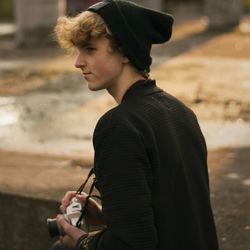 Young man holding camera looking away