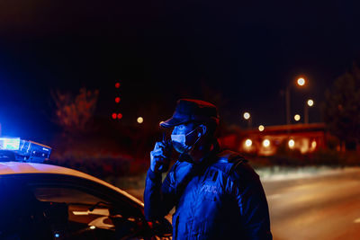 Man standing on illuminated city street during night