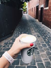 Man holding coffee cup on footpath