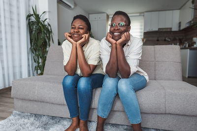 Young woman using mobile phone while sitting on sofa at home