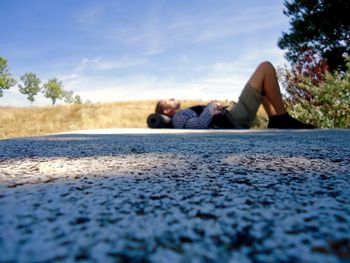 Surface level of man lying down against sky