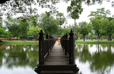 Footbridge over lake against trees