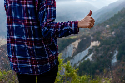 Midsection of man with umbrella standing in background