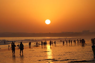 Silhouette people on beach against sky during sunset