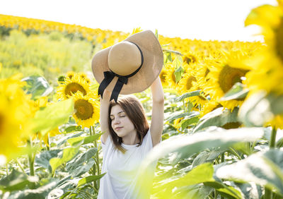 Young beautiful girl walks in the summer in a field with blooming sunflowers