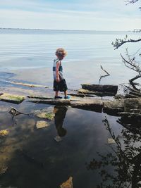 Boy standing in sea against sky