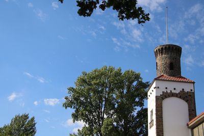 Low angle view of trees and building against sky